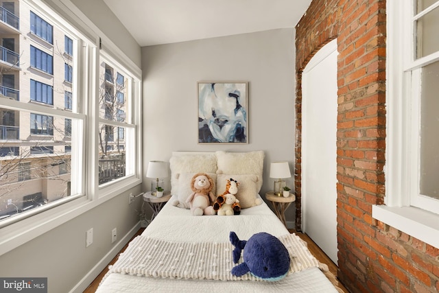 bedroom with brick wall and baseboards