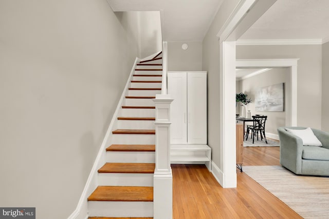 stairs featuring ornamental molding, wood finished floors, and baseboards