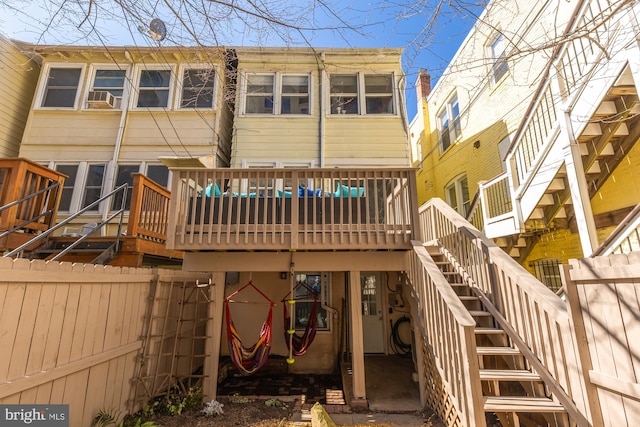 back of property featuring fence, a wooden deck, and stairs