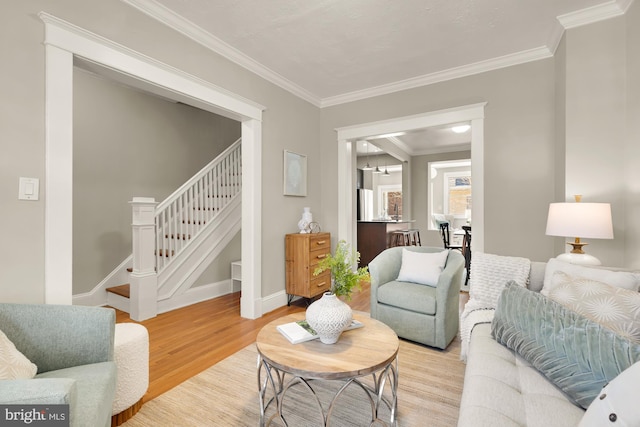 living area with light wood-type flooring, stairs, baseboards, and crown molding