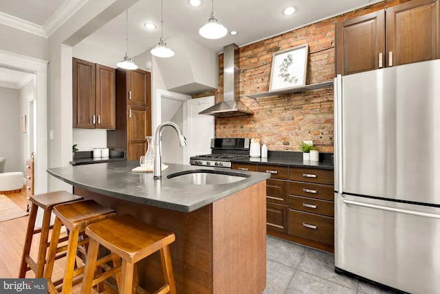 kitchen with a breakfast bar area, stainless steel appliances, ornamental molding, wall chimney exhaust hood, and dark countertops