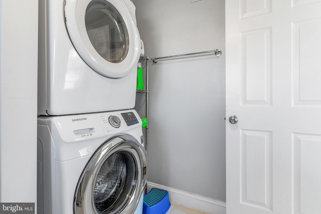 laundry room with stacked washing maching and dryer and tile patterned floors