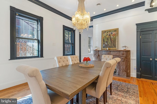 dining room with ornamental molding, light wood-type flooring, and an inviting chandelier