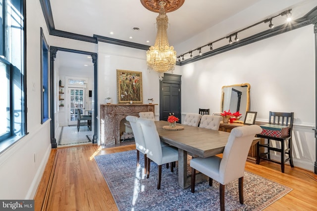 dining room with light wood-type flooring, crown molding, a chandelier, and plenty of natural light