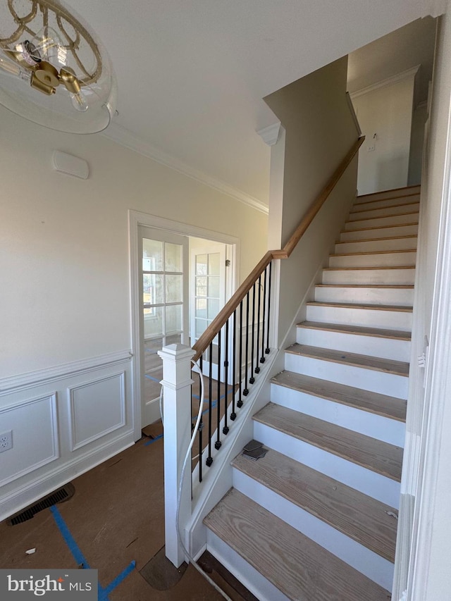 stairs featuring crown molding and wood-type flooring