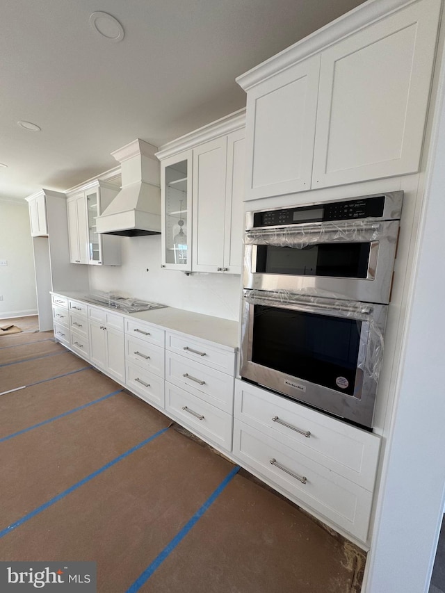 kitchen featuring custom exhaust hood, stainless steel appliances, and white cabinets