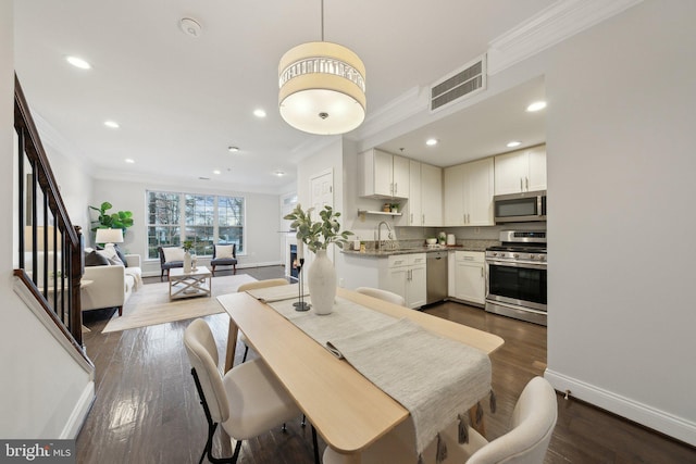 dining space featuring dark hardwood / wood-style floors, crown molding, and sink