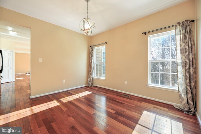 unfurnished room featuring an inviting chandelier and dark hardwood / wood-style flooring