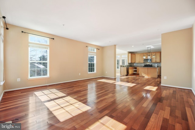 unfurnished living room featuring a wealth of natural light and hardwood / wood-style floors