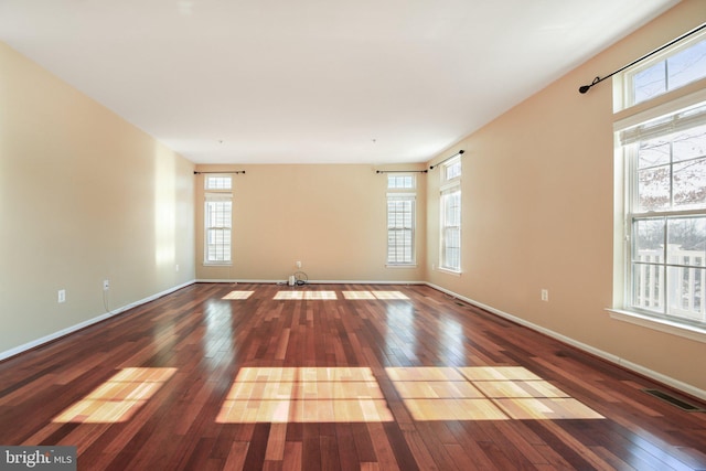 empty room with dark hardwood / wood-style flooring and a wealth of natural light