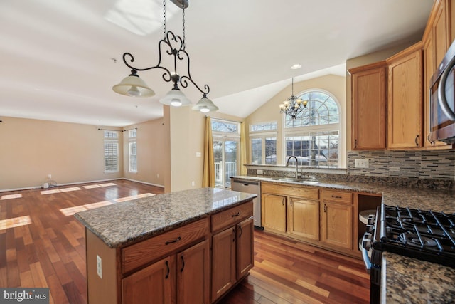 kitchen with appliances with stainless steel finishes, hanging light fixtures, a center island, a notable chandelier, and sink