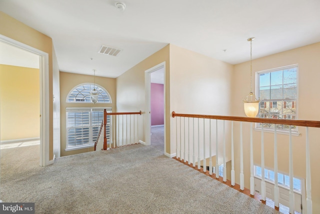 hallway featuring carpet floors and a chandelier