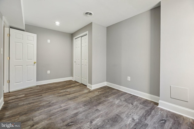 unfurnished bedroom featuring a closet and dark hardwood / wood-style flooring