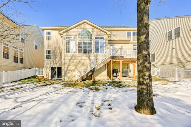 snow covered house with a deck and central AC unit