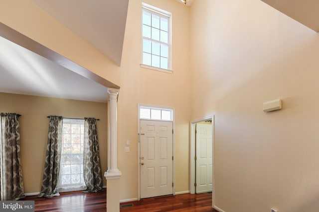 foyer with plenty of natural light, decorative columns, a high ceiling, and dark hardwood / wood-style floors