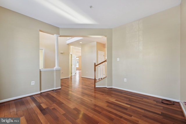 unfurnished room featuring decorative columns and dark hardwood / wood-style floors