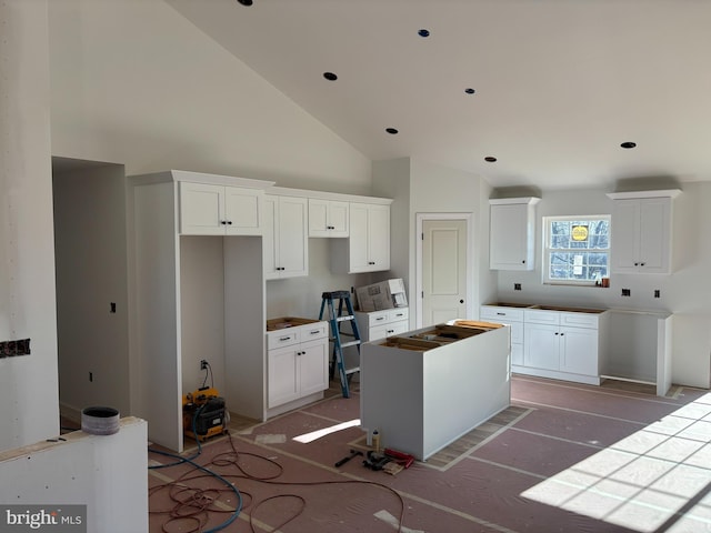 kitchen featuring white cabinetry, a kitchen island, and high vaulted ceiling