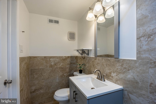 bathroom featuring vanity, toilet, and tile walls