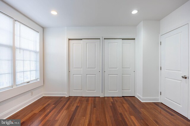 unfurnished bedroom featuring dark hardwood / wood-style floors and two closets