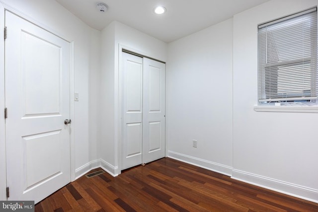 unfurnished bedroom with a closet and dark hardwood / wood-style floors