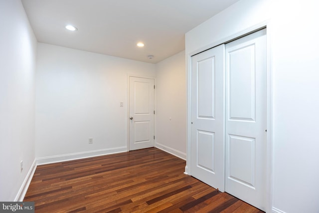 unfurnished bedroom featuring a closet and dark wood-type flooring