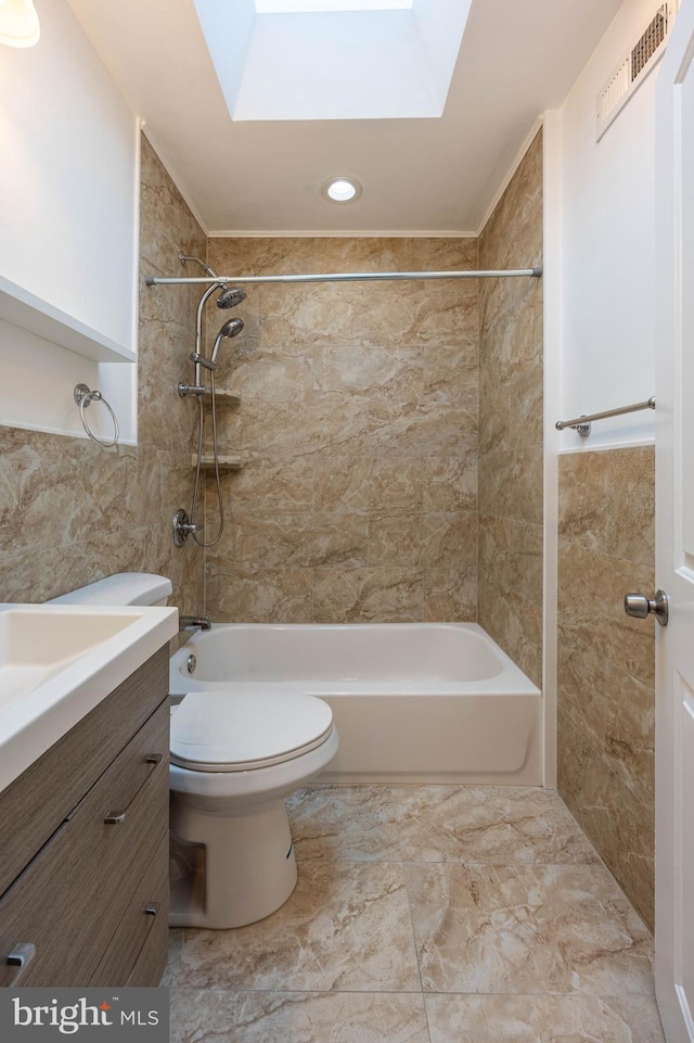 full bathroom with a skylight, vanity, tiled shower / bath combo, and toilet