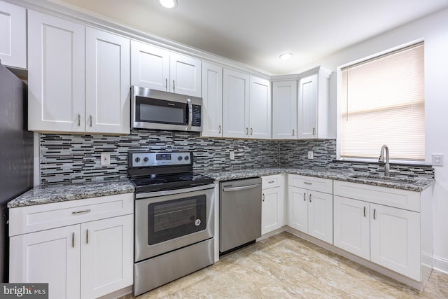 kitchen with stone counters, white cabinetry, sink, and stainless steel appliances