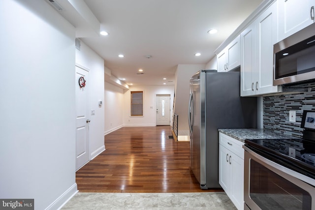 kitchen featuring light stone countertops, appliances with stainless steel finishes, decorative backsplash, hardwood / wood-style floors, and white cabinetry