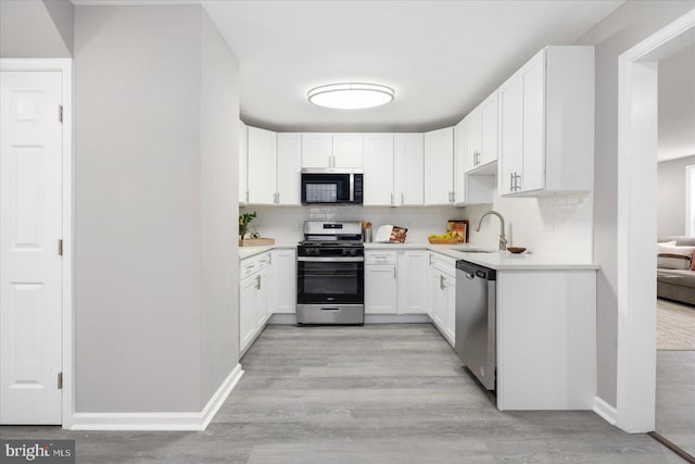 kitchen featuring light hardwood / wood-style flooring, sink, backsplash, white cabinetry, and stainless steel appliances