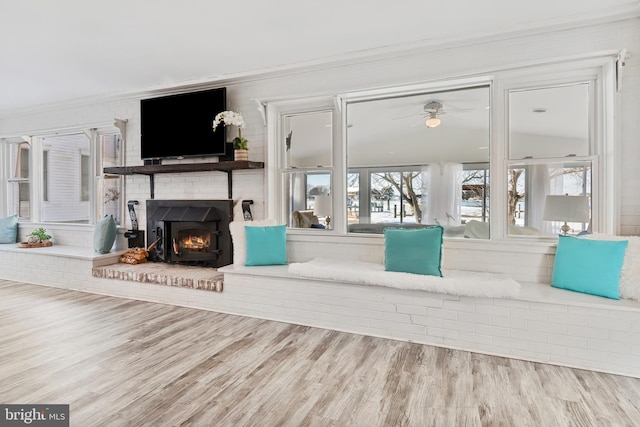 living room featuring hardwood / wood-style flooring, a brick fireplace, and crown molding