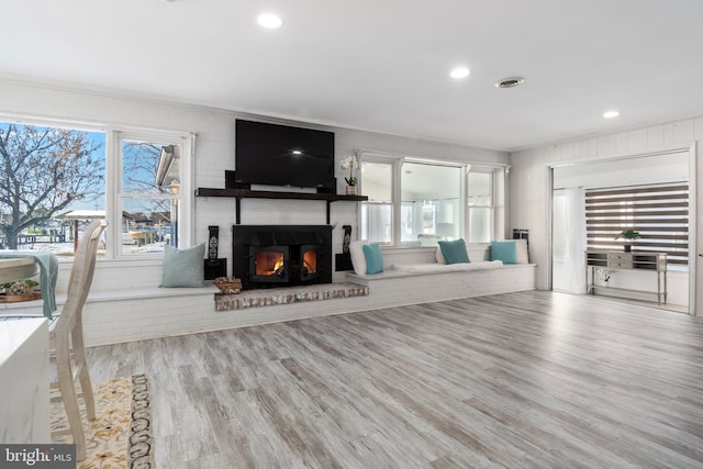 living room featuring a fireplace, light wood-type flooring, and crown molding