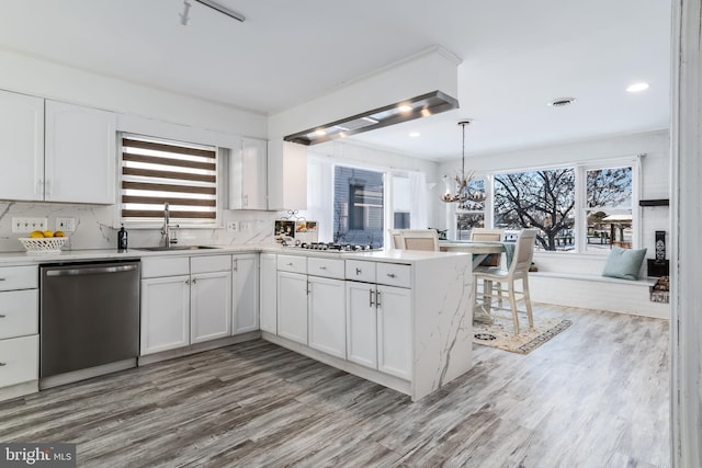 kitchen featuring white cabinets, stainless steel appliances, kitchen peninsula, a wealth of natural light, and sink