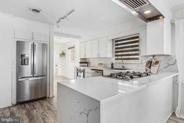 kitchen with sink, white cabinetry, kitchen peninsula, rail lighting, and appliances with stainless steel finishes