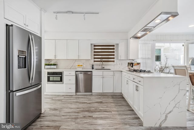 kitchen with light stone countertops, decorative backsplash, white cabinetry, appliances with stainless steel finishes, and sink