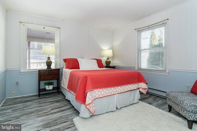 bedroom featuring a baseboard heating unit, ornamental molding, and hardwood / wood-style floors