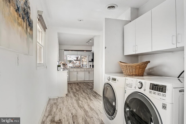 laundry area featuring washer and dryer, track lighting, light hardwood / wood-style floors, and cabinets