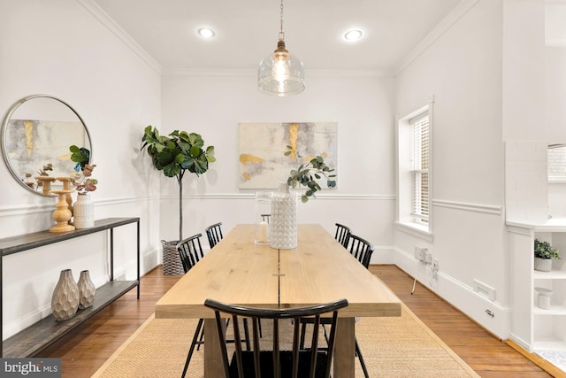 dining space with ornamental molding and light hardwood / wood-style flooring