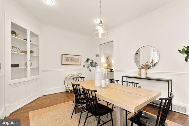 dining area featuring hardwood / wood-style flooring, crown molding, and built in features