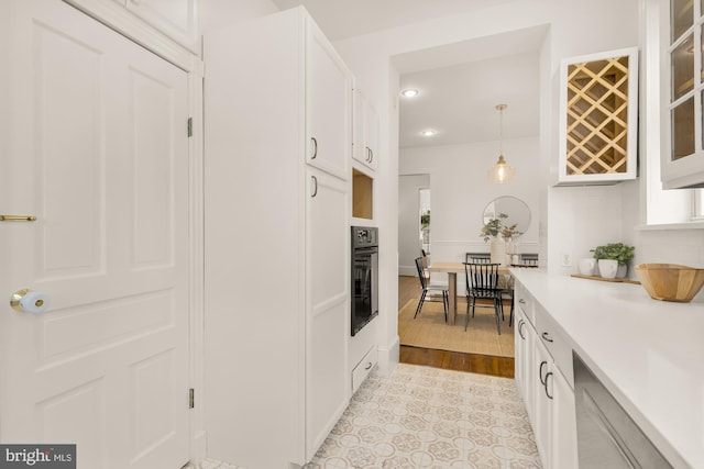 kitchen with white cabinetry, oven, hanging light fixtures, and backsplash