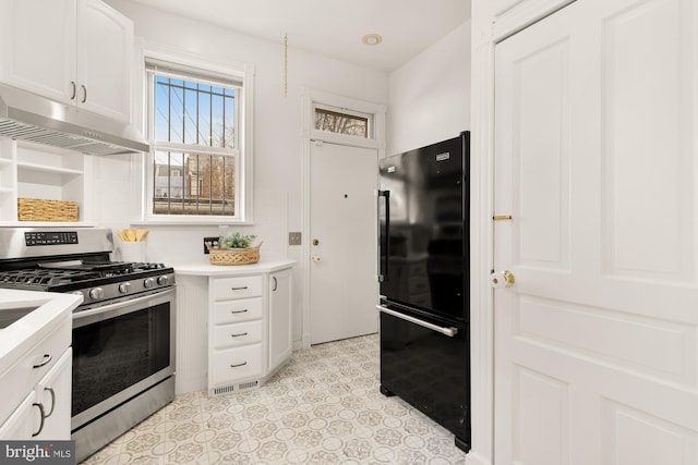 kitchen featuring black refrigerator, white cabinetry, and gas stove