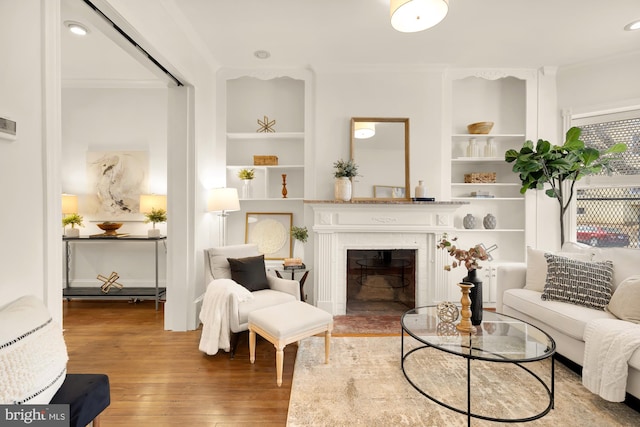 living room featuring hardwood / wood-style floors, ornamental molding, and built in features