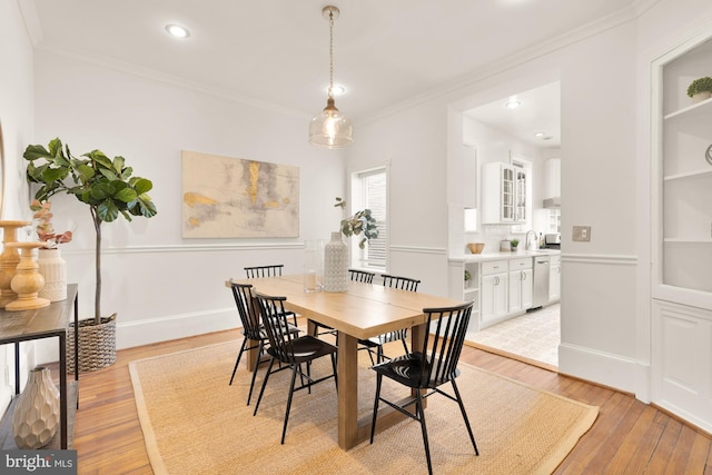 dining area featuring sink, crown molding, and light wood-type flooring