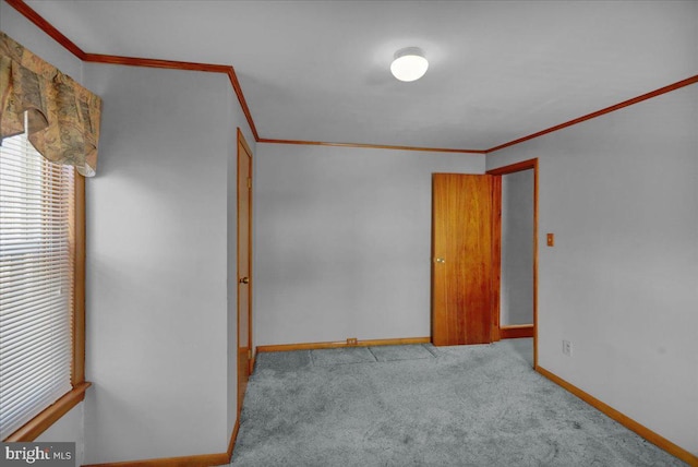 empty room with light colored carpet, crown molding, and baseboards