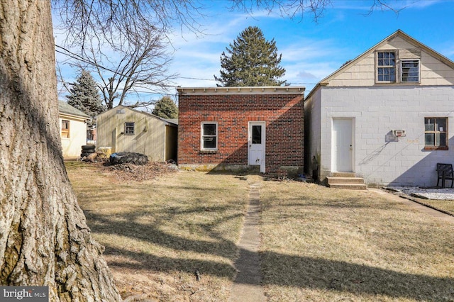 rear view of property with entry steps, a yard, and brick siding