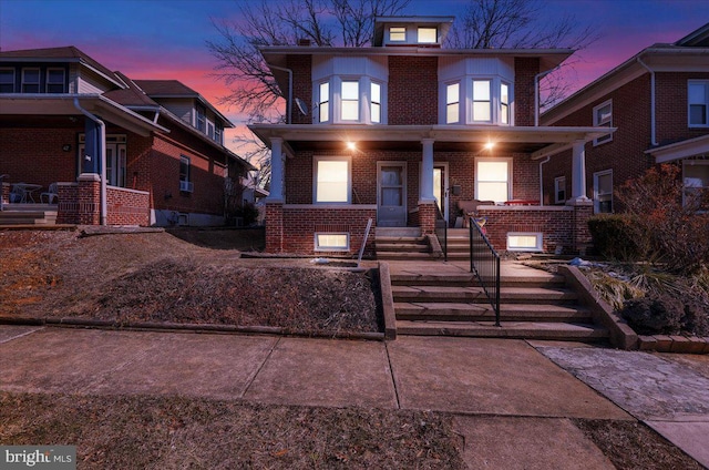 american foursquare style home featuring a porch and brick siding