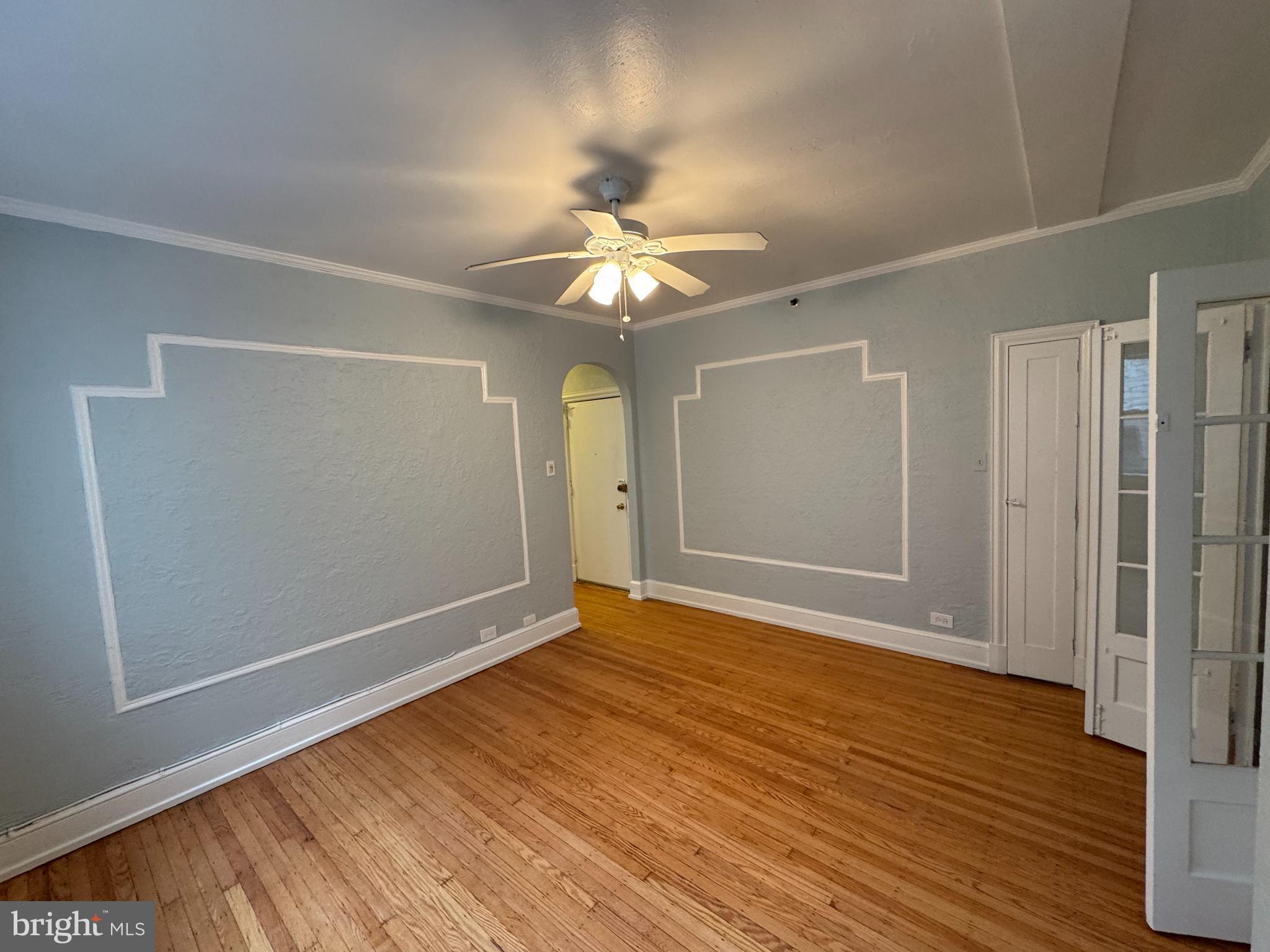 empty room with ceiling fan, light hardwood / wood-style flooring, and crown molding