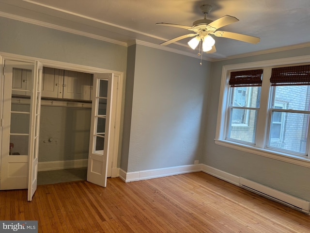 unfurnished bedroom featuring a baseboard heating unit, a closet, ceiling fan, light hardwood / wood-style flooring, and crown molding