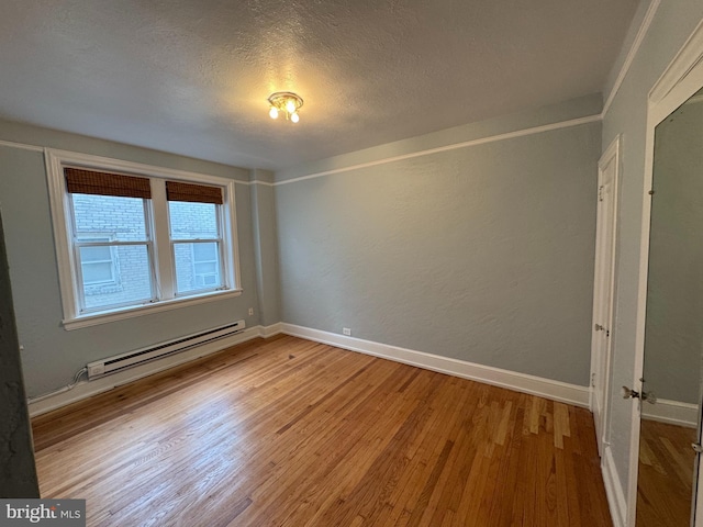 spare room with a baseboard radiator, hardwood / wood-style floors, and a textured ceiling