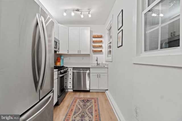 kitchen featuring sink, white cabinetry, stainless steel appliances, and light wood-type flooring