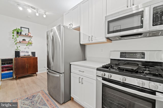 kitchen with light wood-type flooring, stainless steel appliances, and white cabinetry